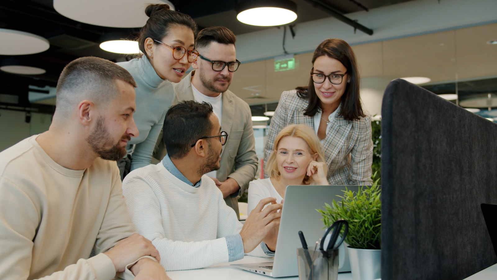 Diverse team collaborating around a laptop in an office
