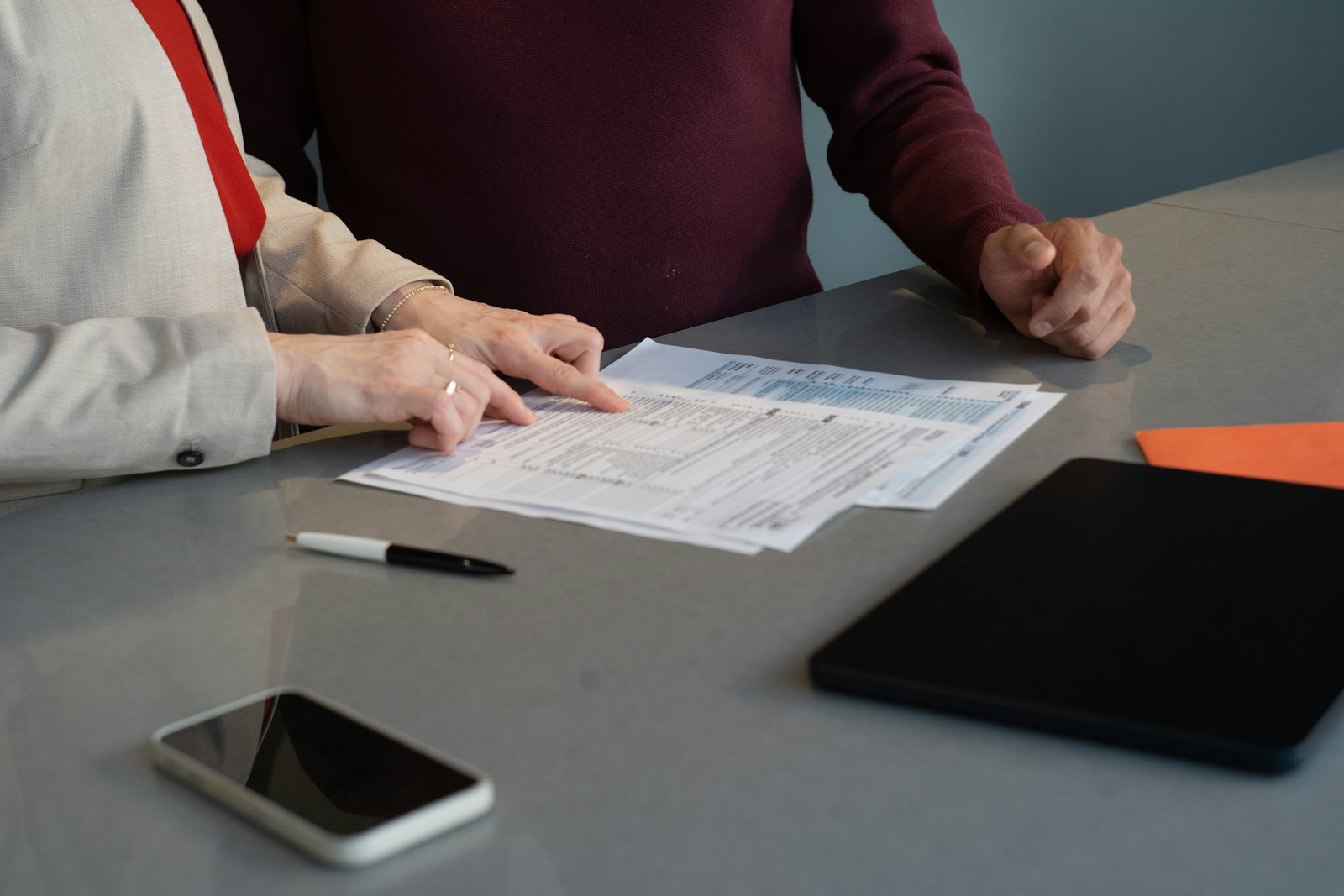 Two professionals reviewing paperwork together at a conference table during a business meeting