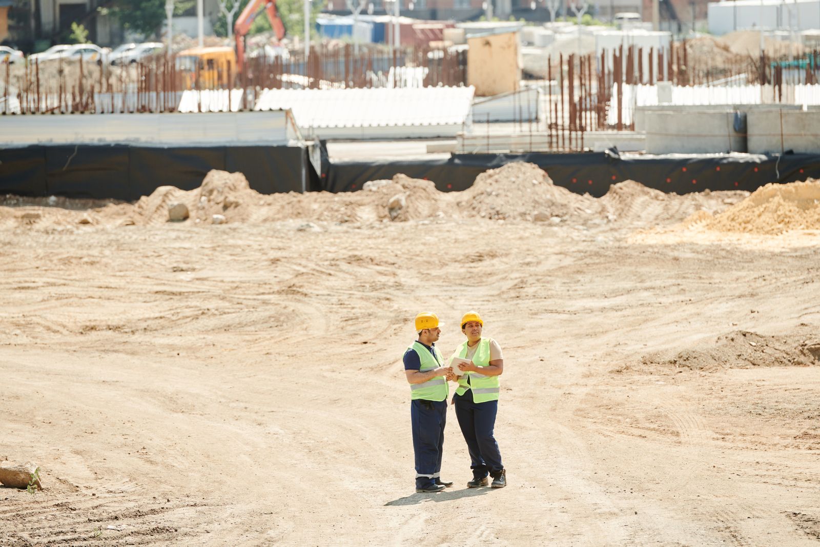 Construction team reviewing plans on site with hard hats and safety gear
