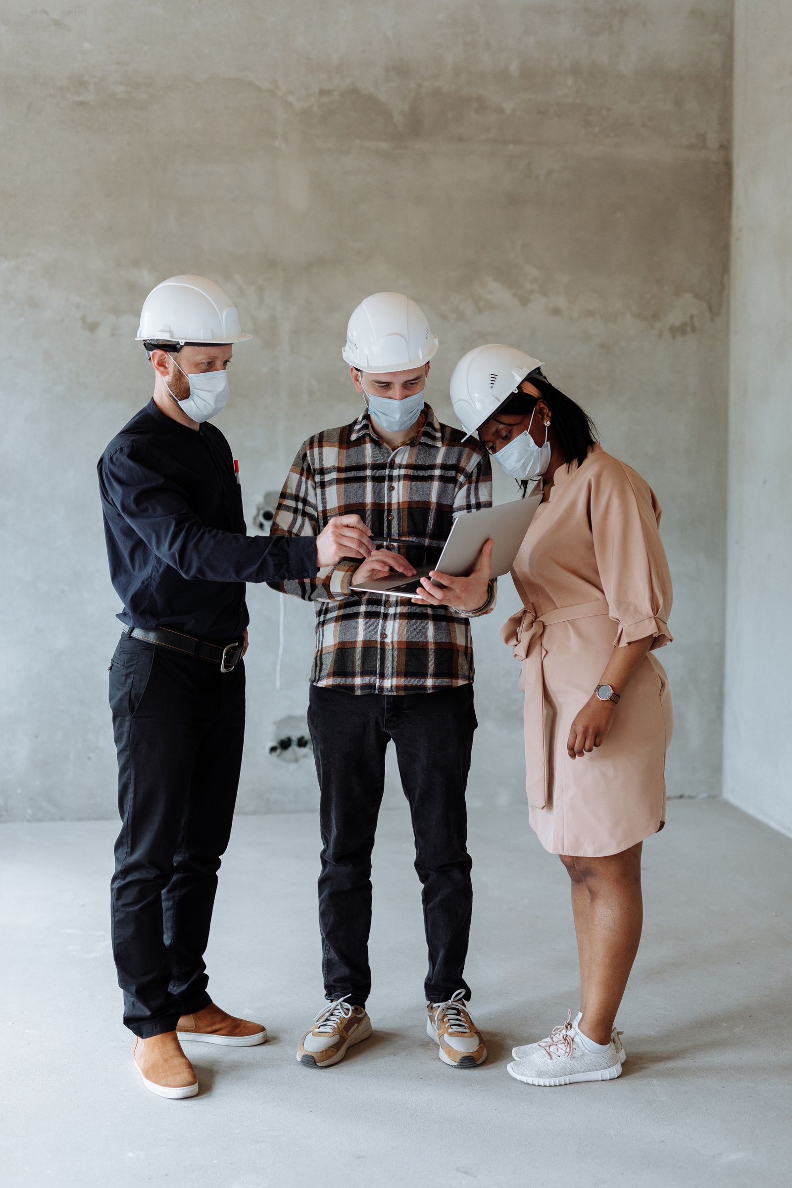 Construction workers collaborating over plans and a tablet on site