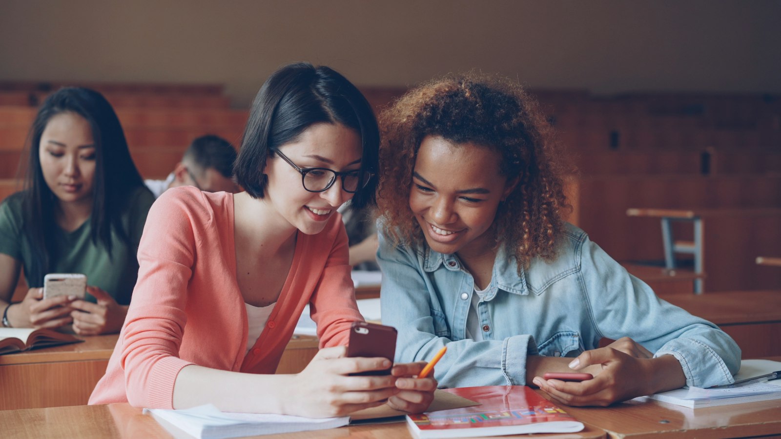 Two students looking at a smartphone together, reviewing content on a mobile learning app