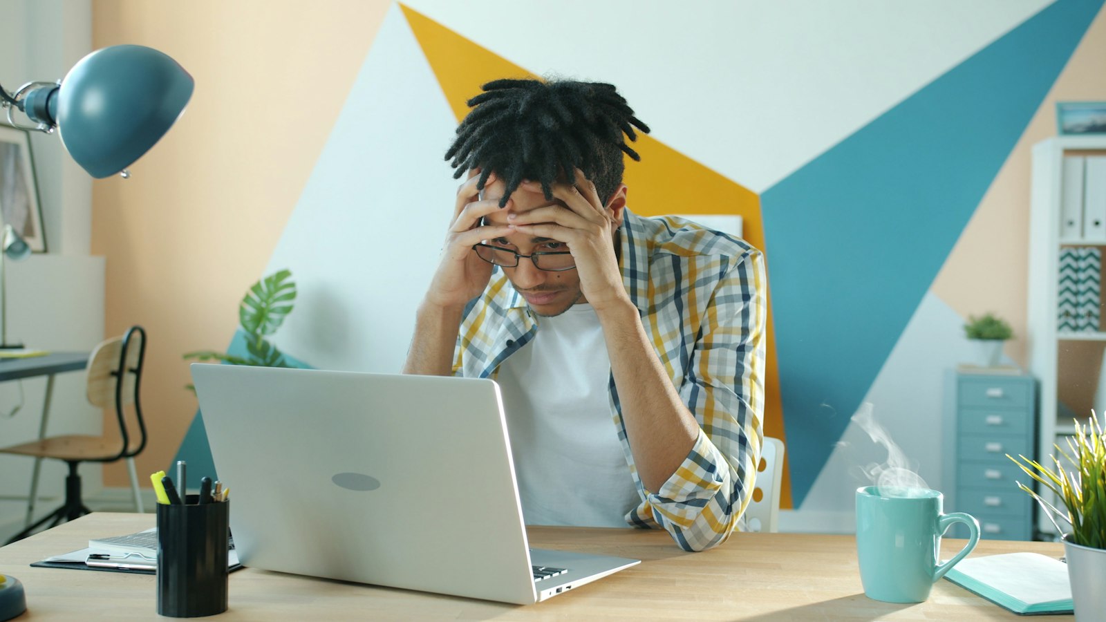 A stressed person looking at a laptop screen in an office, representing a developer facing a production incident